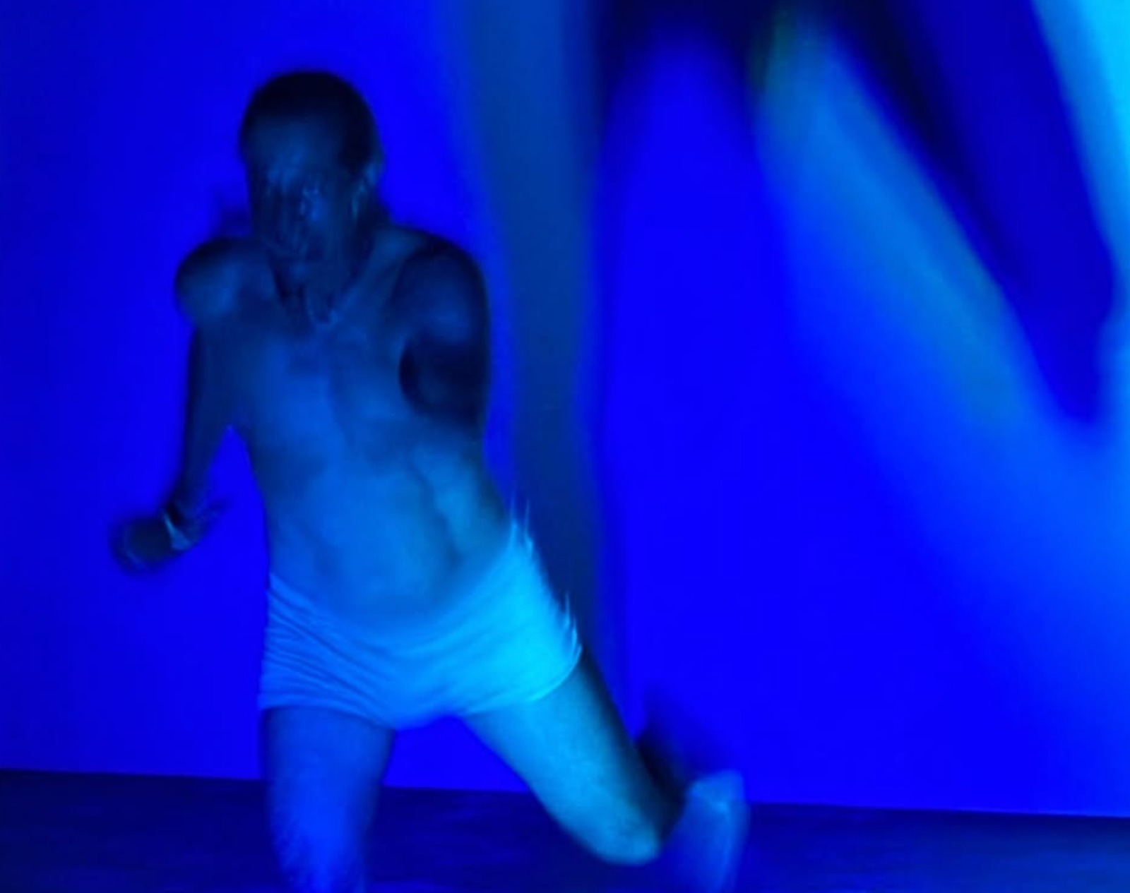 Corpo em movimento desfocado sob luz azul intensa
