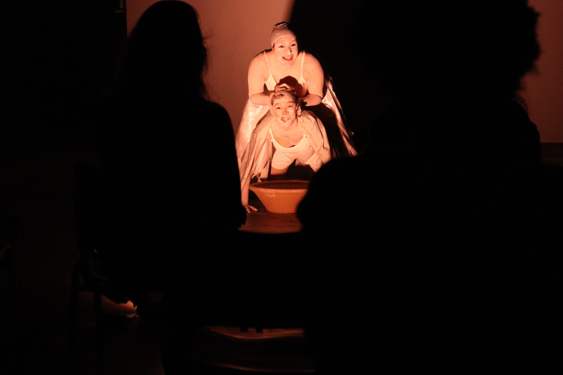 Duas performers em cena de água vistas entre o público