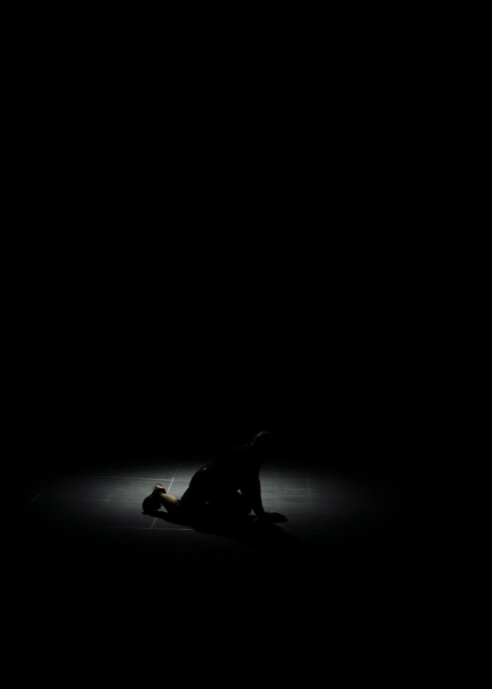 Performer no chão sob feixe de luz durante treinamento